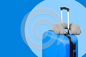 Blue suitcase and travel pillow on a blue background