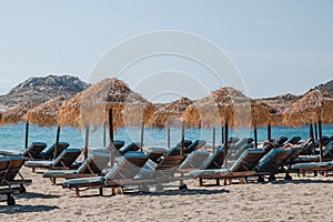 Blue sun beds under parasols on Kalafati beach, Mykonos, Greece, on a sunny summer day photo