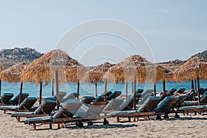 Blue sun beds under parasols on Kalafati beach, Mykonos, Greece, on a sunny summer day photo