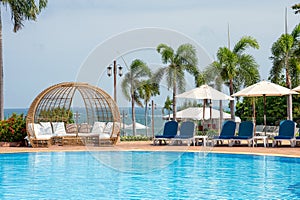 Blue sunbeds with parasol with modern wooden chair on swimming pool