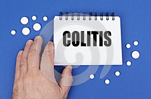 On the blue surface of the tablet, a hand and a notepad with the inscription - COLITIS