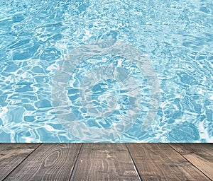 Blue swimming pool rippled water detail with wooden floor