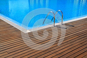 Blue swimming pool with teak wood flooring