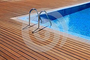 Blue swimming pool with teak wood flooring