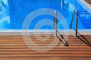 Blue swimming pool with teak wood flooring