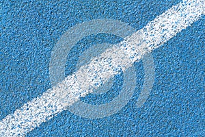 Blue synthetic surface of a track of athletics stadium with white diagonal line as texture, background abstract