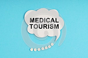 On a blue table are pills and a white plate with the inscription - MEDICAL TOURISM