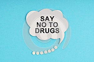 On a blue table are pills and a white plate with the inscription - Say No To Drugs