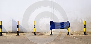 Blue tatter, cotton, rug or fabric hanging on small yellow/Black tower with gray wall photo