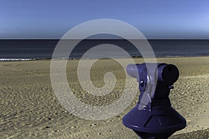 Blue telescope with the beach in the background