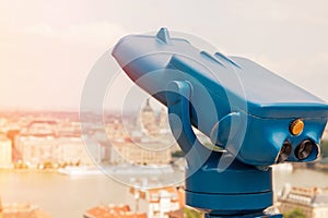 Blue telescope and blurred city on background