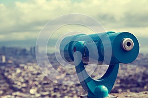 Blue telescope and blurred city on background.