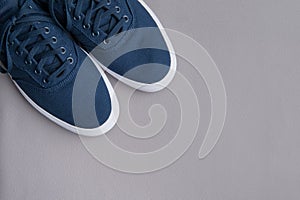 Blue textile sneakers with a white sole on a gray background. Flat lay