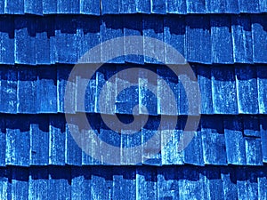 Blue texture of wooden tile roof. Shingle aged wooden Background. Backdrop with small overlapping colored wooden shingles on roof