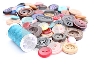 Blue thread with needle and collection of colored sewing buttons