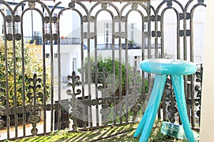 Blue three-legged stool on a balcony with beautiful iron railings and plant decorations