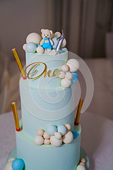 a blue three-tiered cake decorated with bear cub and caramel balls