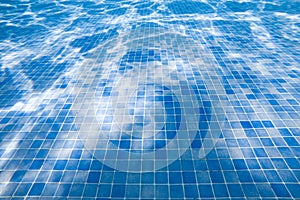Blue tiled floor inside underwater swimming pool with light difraction effecte