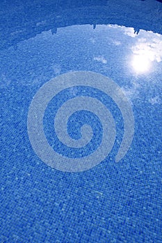 Blue tiled swimming pool with sun reflexion