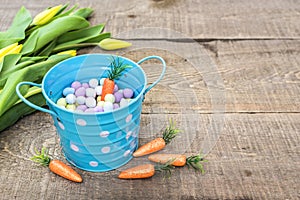 Blue tin polka dot bucket filled with candy eggs and carrot, on