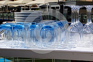 Blue tinted tumblers and wine glasses with plates stacked in a r photo