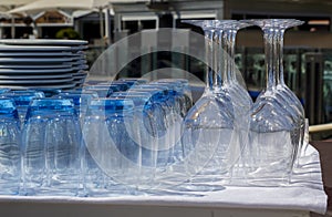 Blue tinted tumblers and wine glasses with plates stacked in a r photo