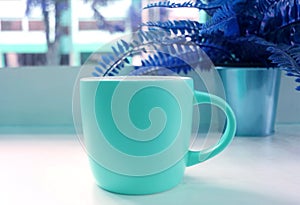 Blue tone colored pop art style coffee cup with the potted fern in the backdrop