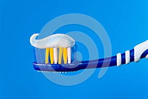 Blue toothbrush with blue toothpaste on a blue background.