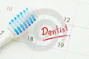 Blue toothbrush on dentist appointment reminder on a calendar. photo