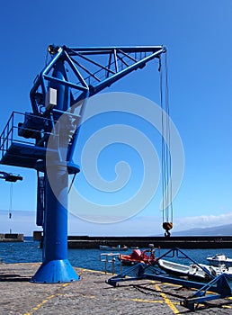 Blue tower crane in a harbor dockyard with sea and boat