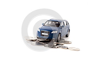 Blue toy iron car with coins on a white background. concept of earnings, income and high cost