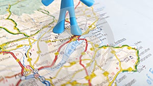 A blue toy man standing over Dundee on a map of Scotland portrait
