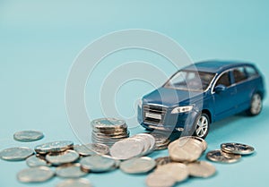 Blue toy SUV car crashed into a stack of money, car insurance concept