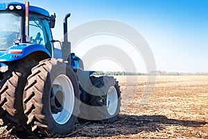 Blue tractor on the background of an empty field