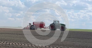 Blue tractor cultivator or seeder plows the land, prepares for crops. dust little planet inside green grass round frame background