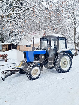 a blue tractor with large wheels in a snowy forest.