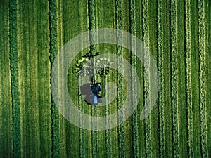 Blue tractor mowing green field, aerial view