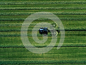 Blue tractor mowing green field, aerial view