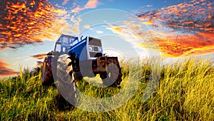 Blue tractor parked on a sloped grass field.