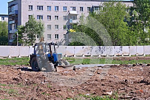 Blue tractor works on construction site fenced