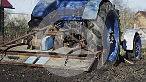 Blue tractor with a your rototiller handles the plot of land.