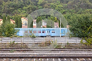 Blue train parked in a residential area, along a set of railroad tracks