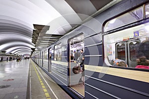 Blue train with passengers standing near platform to subway stat