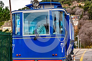 Blue tram with number seven on its sides traveling on street going up a hill