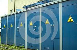 Blue transformer box.Locked electric metal door with a sign of attention on the blue wall of the transformer substation