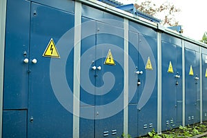 Blue transformer box.Locked electric metal door with a sign of attention on the blue wall of the transformer substation