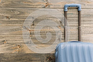 blue travel suitcase against wooden background. High quality photo