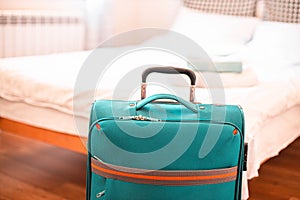 Blue travel suitcase in hotel room. Vacation and travel concept