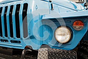 Blue truck front close-up with radiator grille and headlights