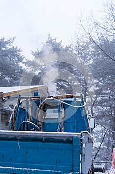 Blue truck parks in a white winter forest full of snow